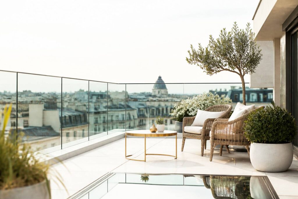 Terrasse sur le toit avec garde-corps en verre et fauteuils en rotin